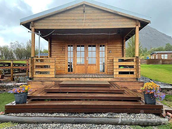 Cabin with porch and double glass doors with a misty mountain backdrop