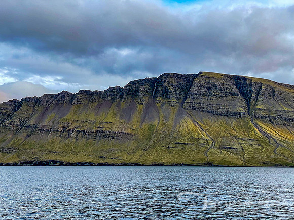 Towering mountainside stands above the fjord