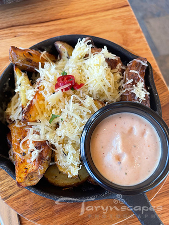 Crisp potato wedges topped with cheese in a small cast iron skillet.