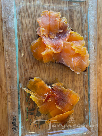Dense dark brown geysir bread is topped with pink smoked salmon