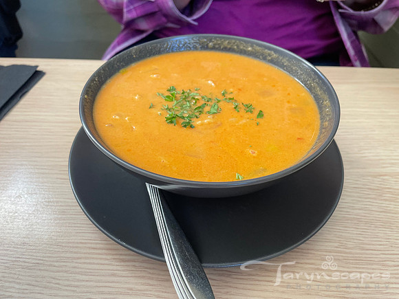 Burnt orange soup in a black bowl topped with cilantro