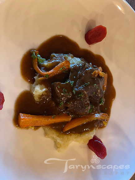 A dollup of mashed potatoes topped with dark meat, carrots and gravy