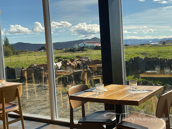Full length windows look out of a pasture of happy cows, blue skies and fluffy clouds