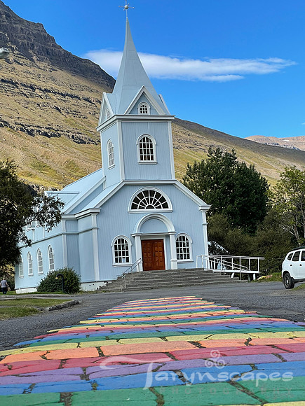 A rainbow painted path leads up to a white church