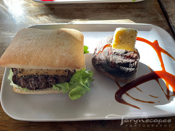 Hamburger on cibatta bun with a potato speared with butter