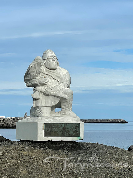 Statue of Loki the viking and his raven on the edge of the sea