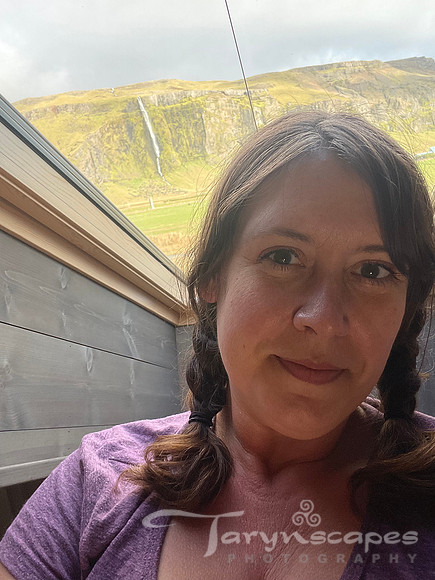 Smiling me with braided pigtails, behind me a sloped skylight looks at the tall skinny waterfall