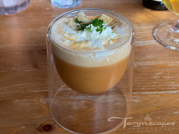 Large shot glass of langastine soup topped with cream and herbs
